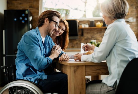 young-happy-couple-their-financial-advisor-using-touchpad-meeting-home-focus-is-man-wheelchair